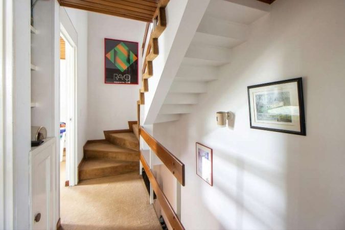 Décoration murale avec cadres et affiches pour valoriser un couloir menant à un escalier.