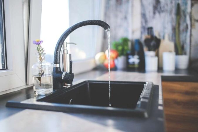 Un robinet mitigeur noir élégant au-dessus d'un évier sombre dans une cuisine lumineuse.