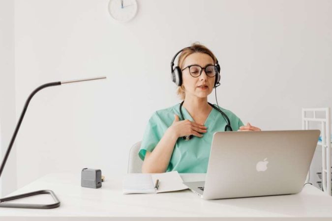 Un médecin de garde en consultation vidéo avec un ordinateur portable et un casque audio.
