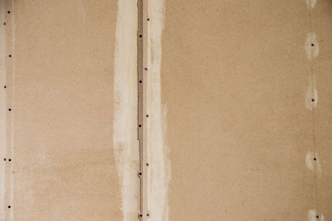 Gros plan sur un panneau de particules avec des joints de colle à bois clairs et des trous de fixation sur une surface texturée.